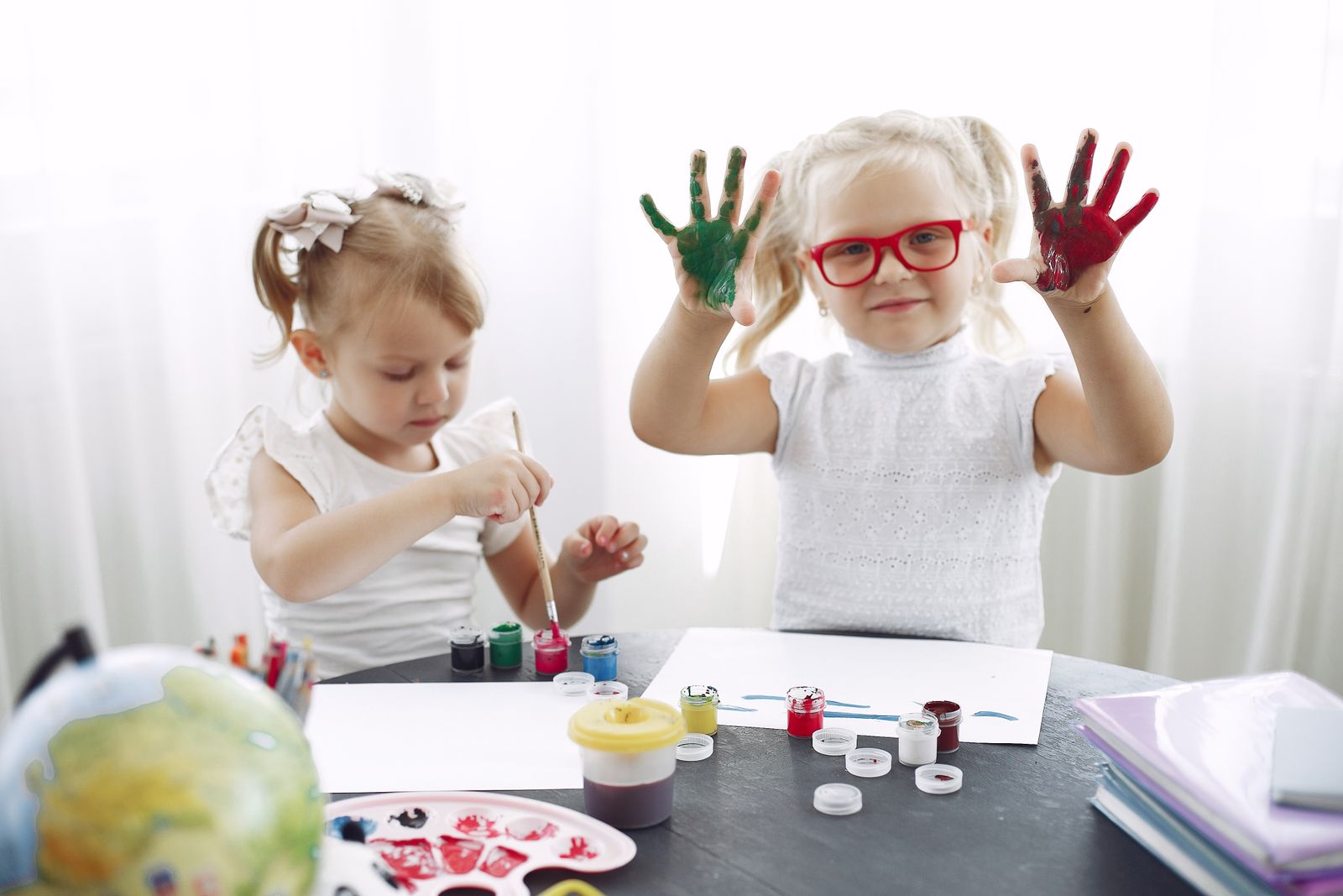 Two children painting together at a colorful art table