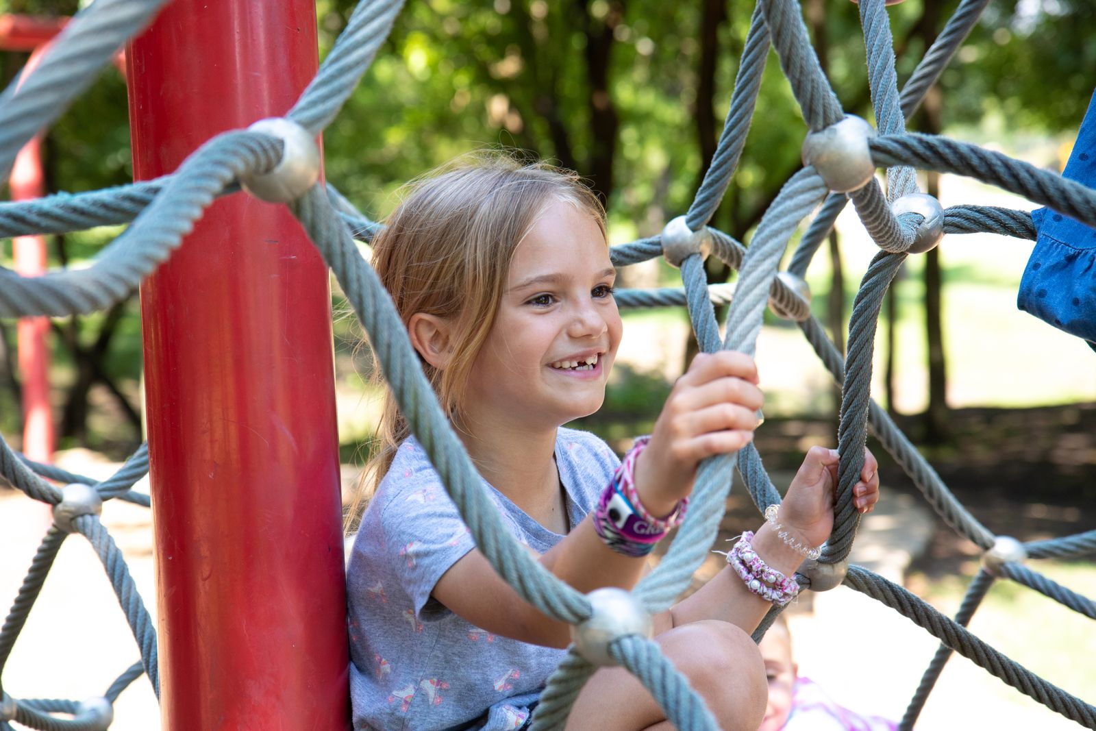 A child climbing a rope structure in a green playground
