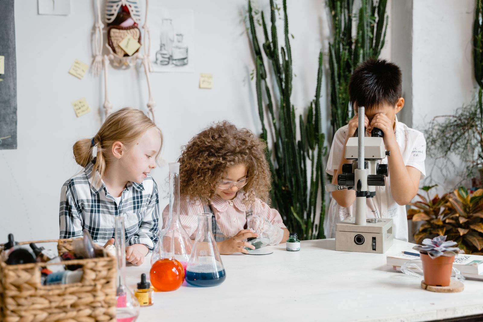 Children exploring a microscope and science materials at a classroom table