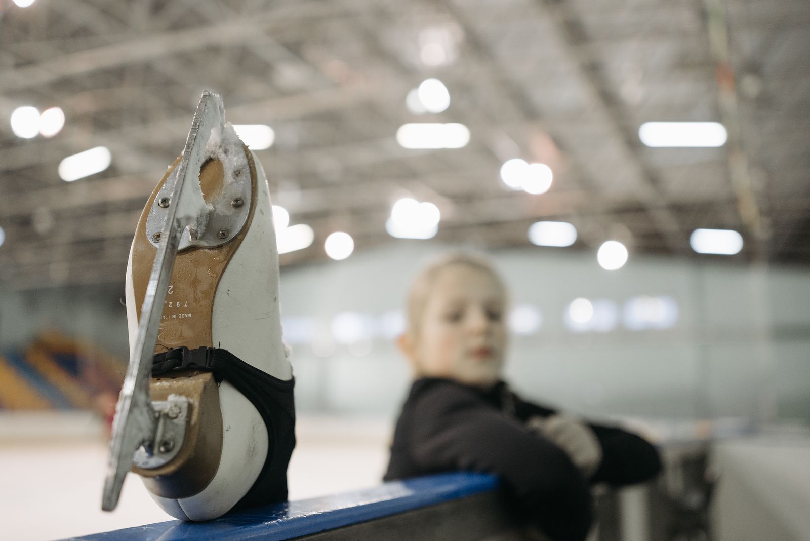 A child wearing ice skates beside an indoor rink