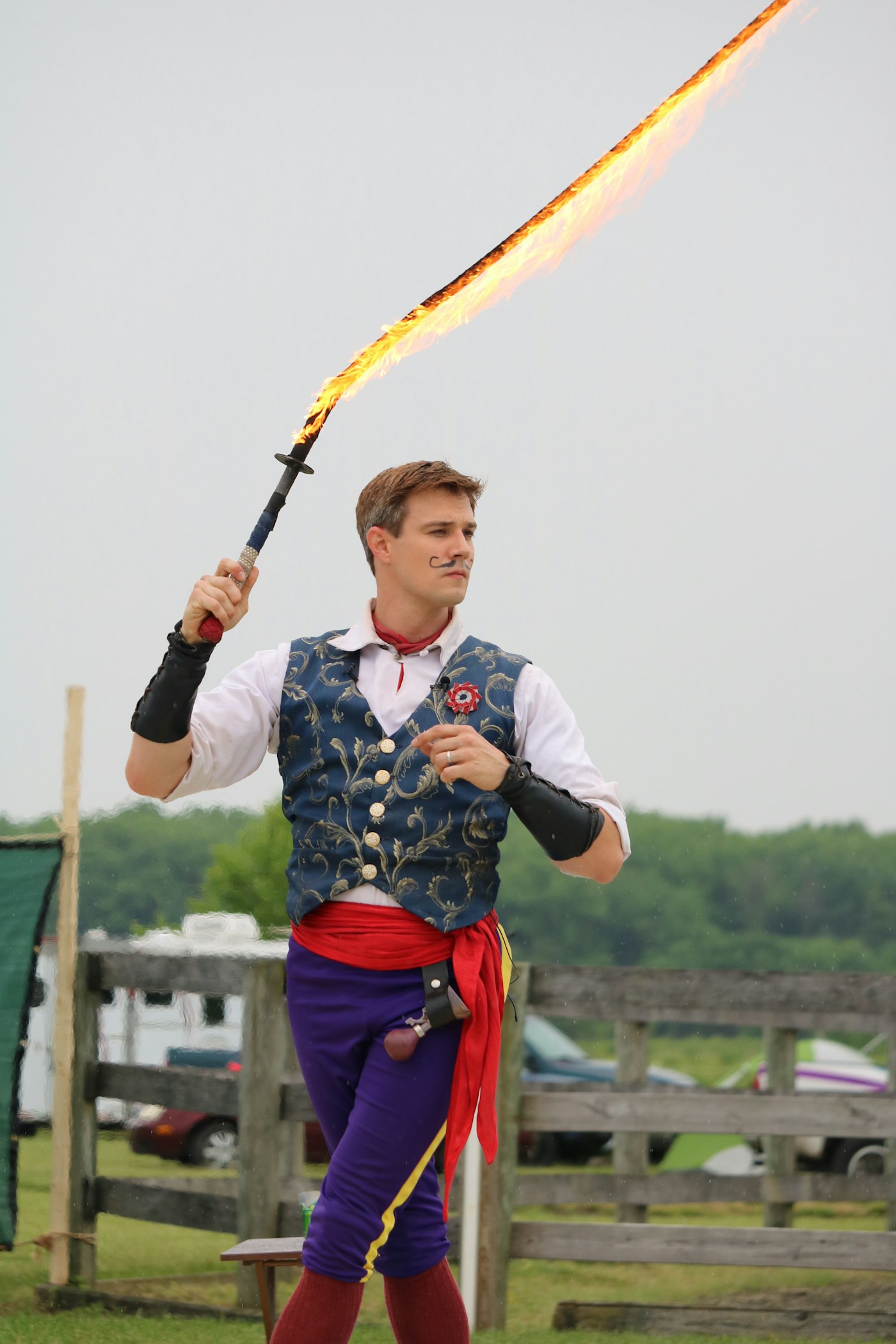 A costumed Renaissance fair performer holding a flaming prop
