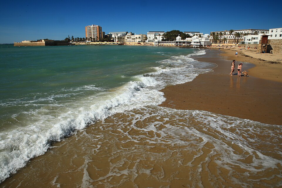 Waves washing onto La Caleta beach beside the waterfront of Cadiz, Spain