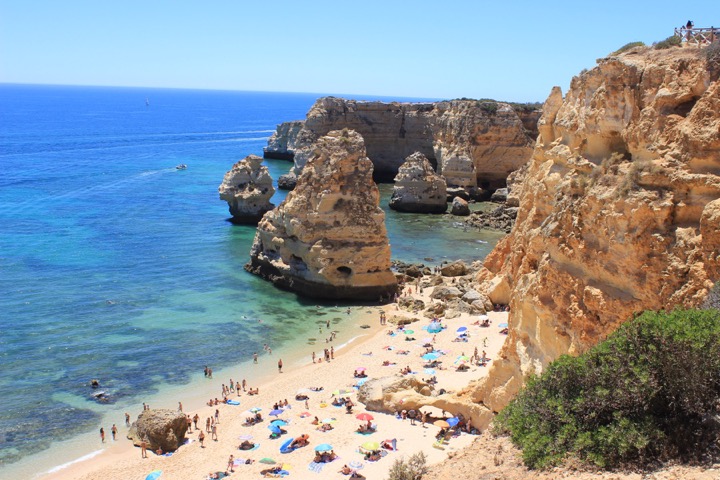 Golden cliffs and turquoise water above a busy Praia da Marinha beach in the Algarve, Portugal