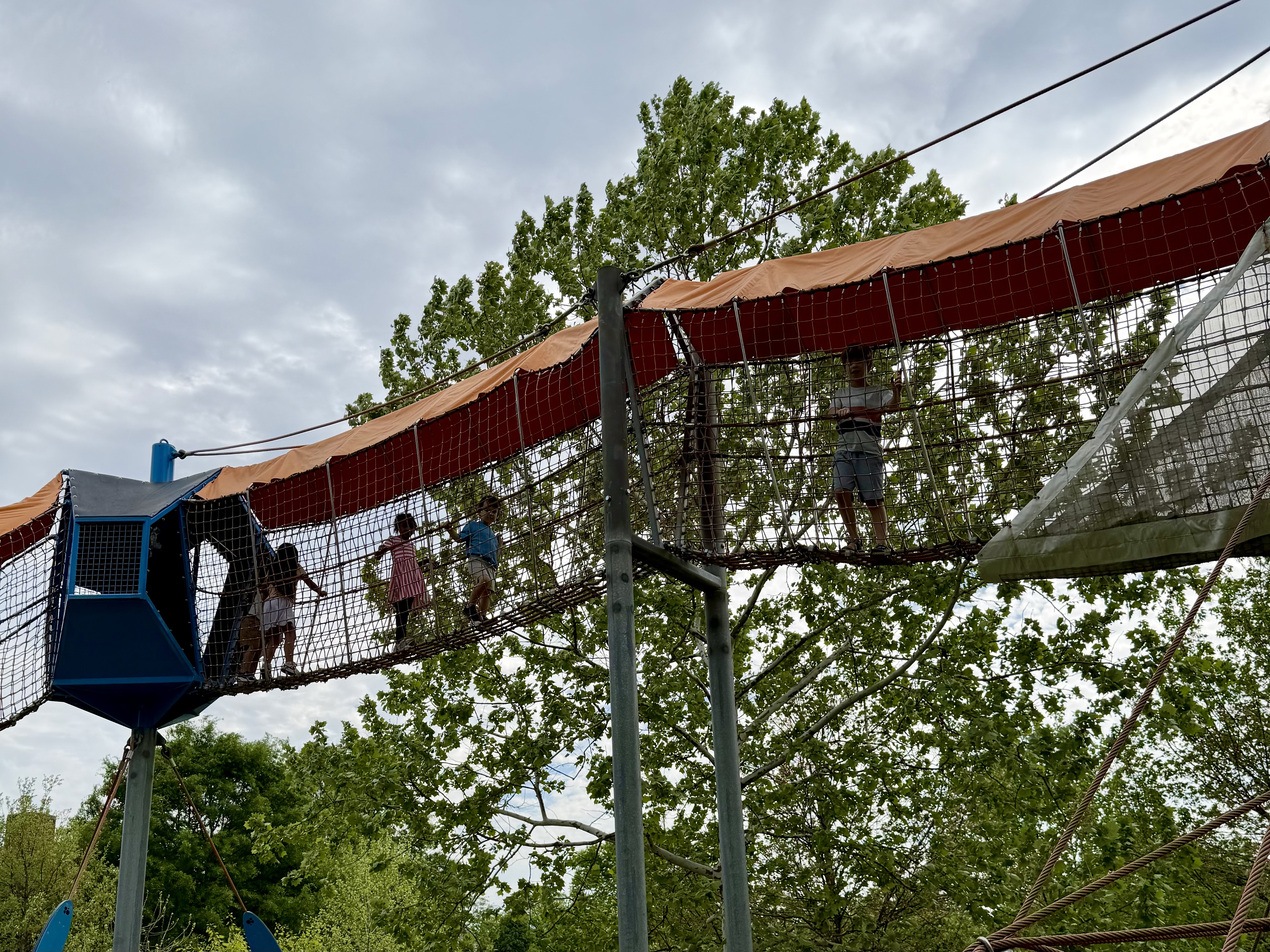 Elevated net climbing bridge and blue play tower at Fairlington Playground in Arlington, Virginia