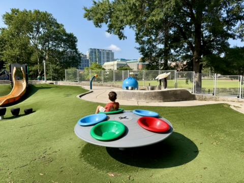 Colorful spinning play equipment, green turf and slides at Quincy Park in Arlington, Virginia